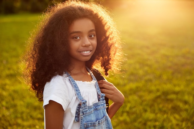 Colegial negra satisfeita com mochila no parque