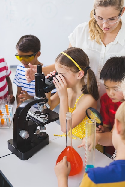 Colegial olhando através do microscópio no laboratório