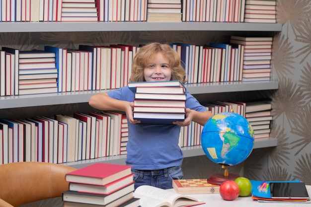 Colegial con pila de libros en la biblioteca escolar años de edad con libro volver a la escuela poco