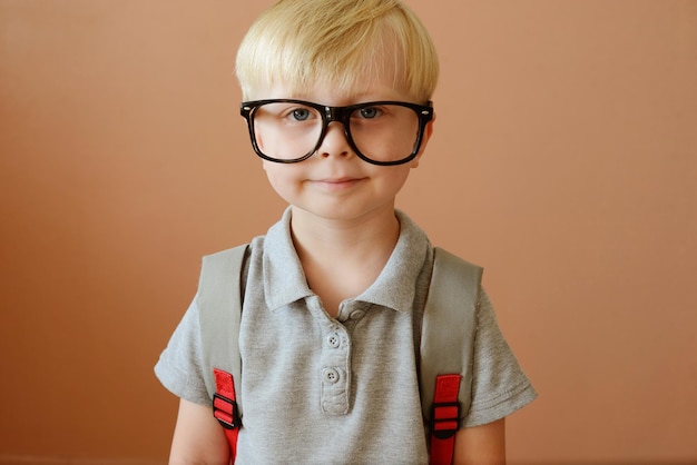 un colegial rubio con gafas y una mochila