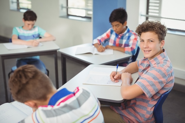 El colegial sentados frente al escritorio en el aula