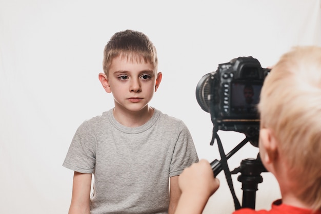 Colegial serio dando una entrevista, el niño con la cámara de video. Joven video blogger.