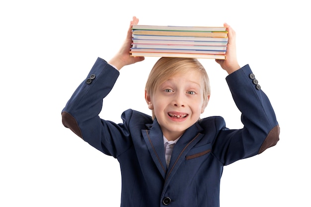 Un colegial sonriente con uniforme escolar sostiene una pila de libros en la cabeza Retrato de un estudiante de escuela primaria Aislado sobre fondo blanco