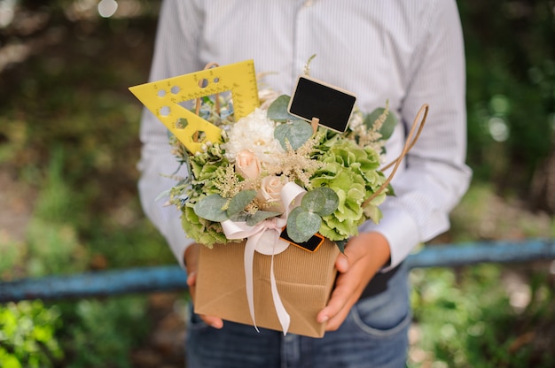 Colegial sosteniendo una caja festiva con flores decoradas con una regla