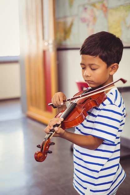 Colegial tocando el violín en el aula