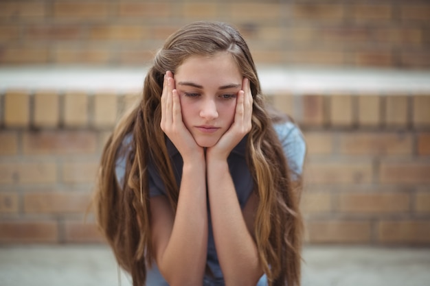 Colegial triste sentada sozinha no campus