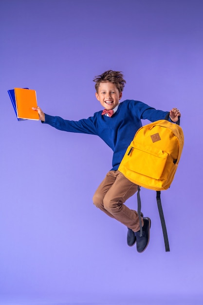 El colegial en uniforme con una mochila saltando