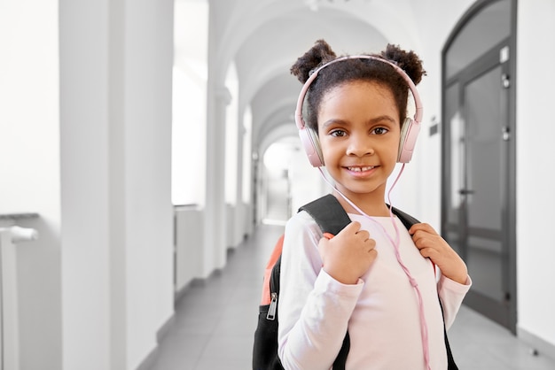 Foto colegial usando fones de ouvido em pé no corredor