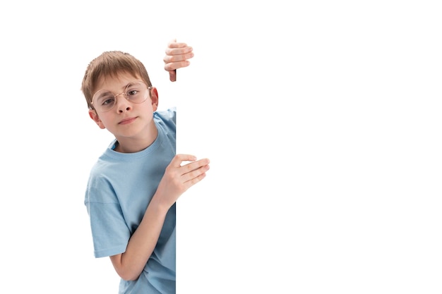 Colegial en vasos grandes con tablero blanco vacío en las manos Niño anunciando su texto en un cartel con espacio de copia Aislado sobre fondo blanco