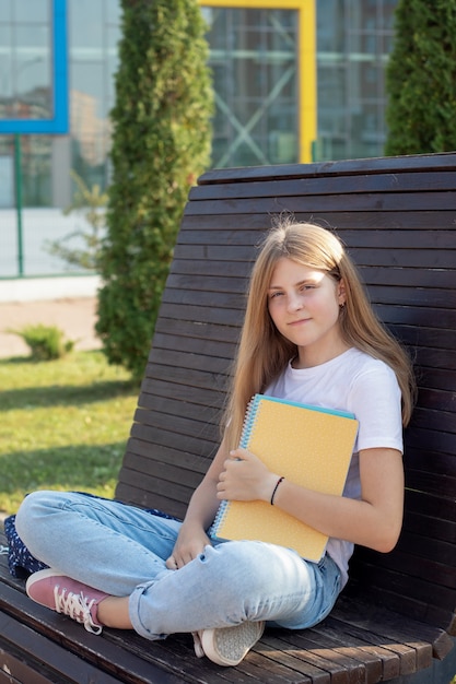 Colegiala adolescente en la calle sosteniendo cuadernos Shes sonriendo feliz concepto educación