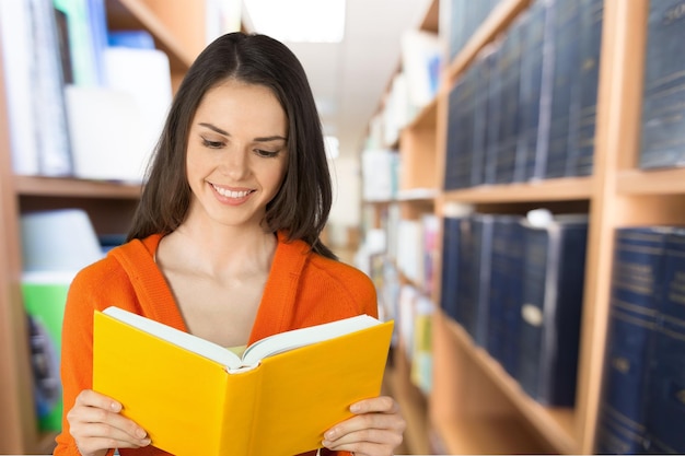 Colegiala adolescente sonriente con libro en el campus de la escuela