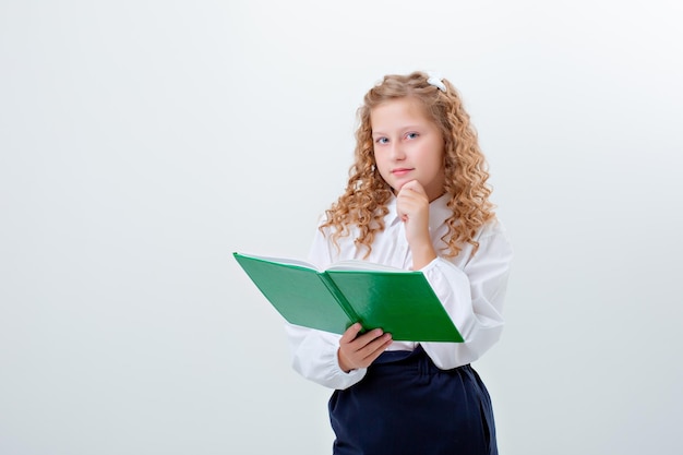 Colegiala adolescente en uniforme escolar sosteniendo un libro sobre un fondo blanco.