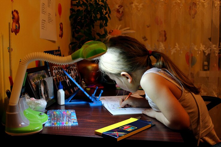 Foto una colegiala aprende lecciones en la mesa de su habitación.