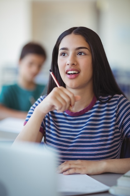 Colegiala atenta estudiando en el aula