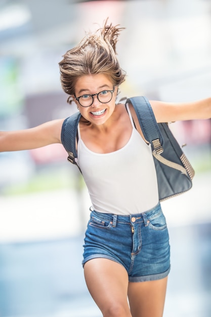 Colegiala atractiva joven con una bolsa llena de la alegría de correr.