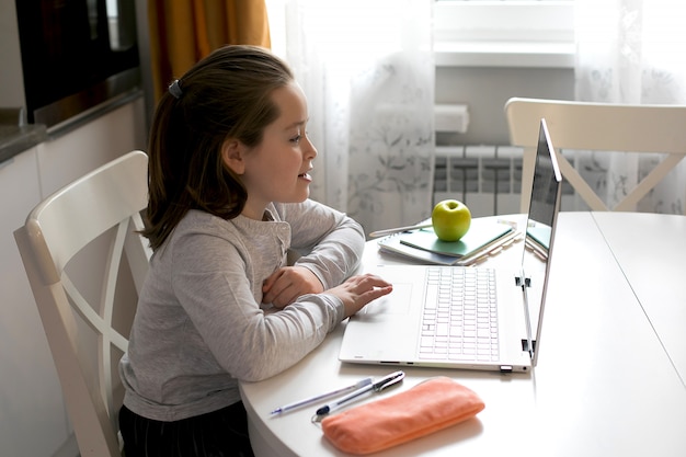 Colegiala bastante linda que estudia en casa usando la computadora portátil.