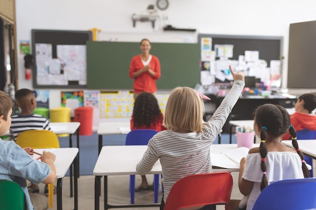 Colegiala caucásica levantando la mano en el aula en la escuela