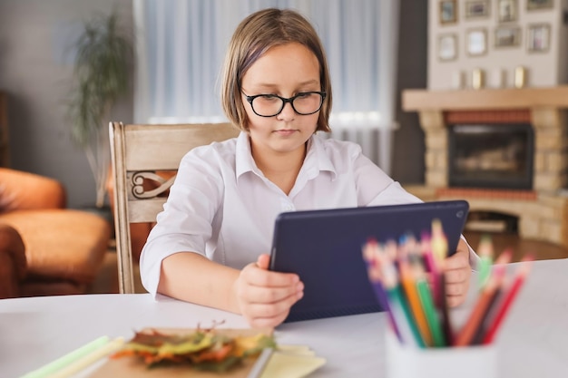 Colegiala dedicada a la educación en el hogar viendo una conferencia de aprendizaje en línea en una computadora portátil en casa Niño que asiste a una clase de escuela virtual remota escuchando al maestro Aprendizaje remoto en casa con tecnología