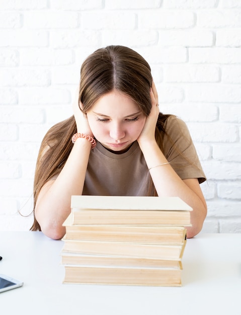 Colegiala deprimida con una pila de libros