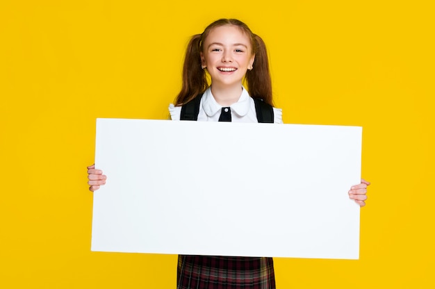 Colegiala elemental sosteniendo un tablero blanco