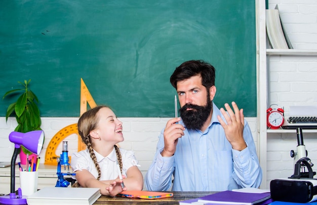 Colegiala estudia libro de texto padre e hija estudian en educación y conocimiento en el aula regreso a la escuela matemáticas geometría hombre barbudo maestro con niña pequeña en clase biología química lección