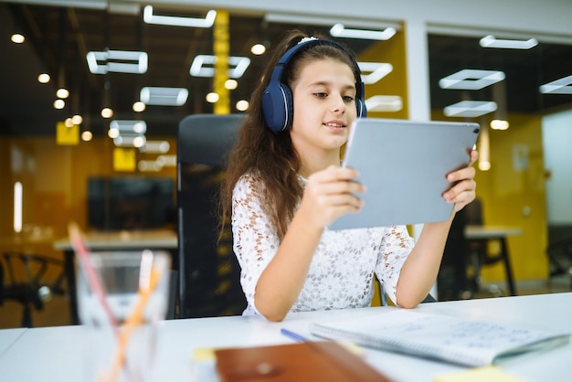 Colegiala estudiando la tarea durante su lección en línea en casa con tableta Distancia social,