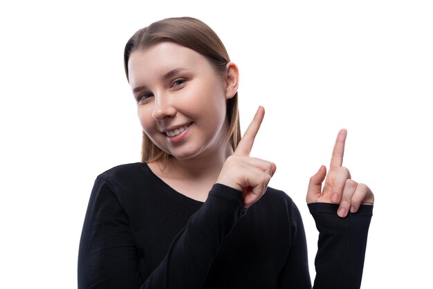 Foto una colegiala europea sonriente vestida con una blusa negra informa las noticias con su dedo