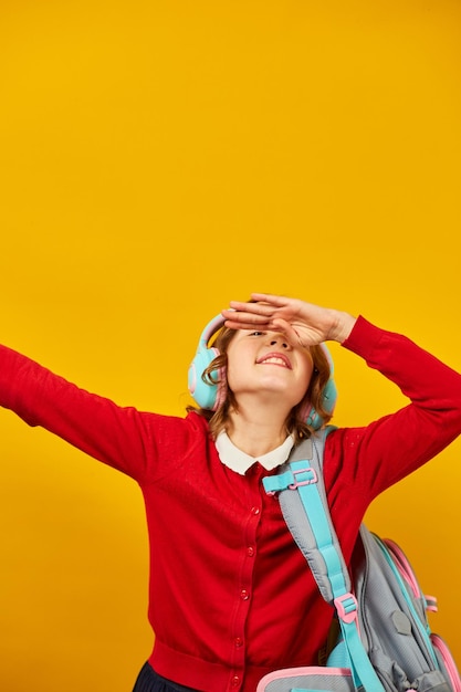 Colegiala feliz con auriculares de mochila divirtiéndose