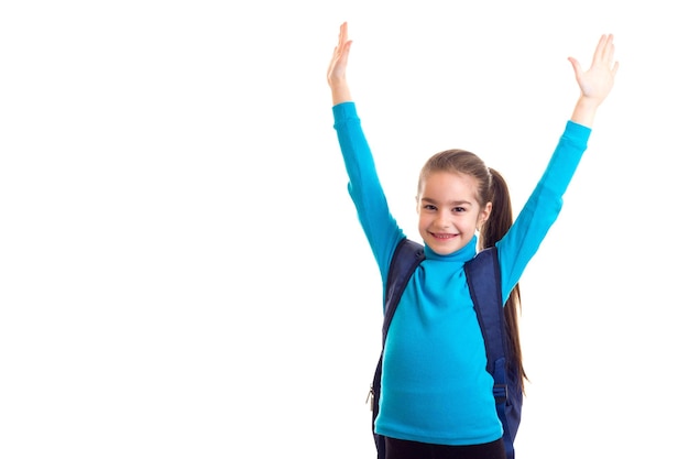 Colegiala feliz con bolsa con las manos arriba en fondo blanco aislado.