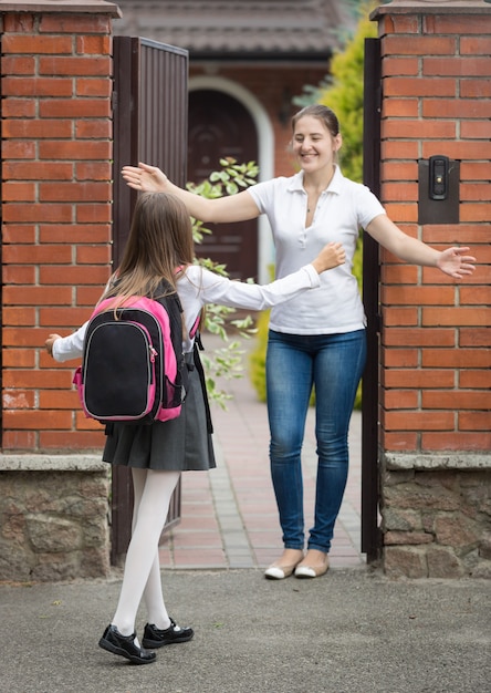 Colegiala feliz corriendo a su madre esperándola después de la escuela