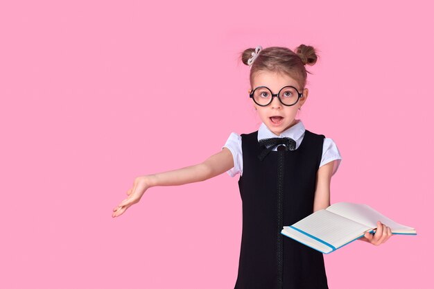 Colegiala con gafas redondas y uniformes sin lentes sostiene un cuaderno en sus manos