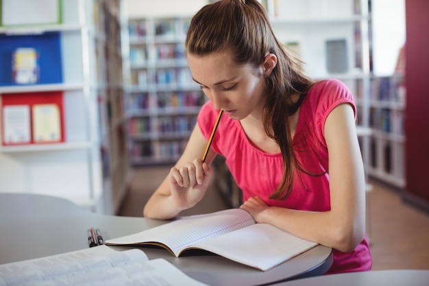 Colegiala haciendo los deberes en la biblioteca de la escuela