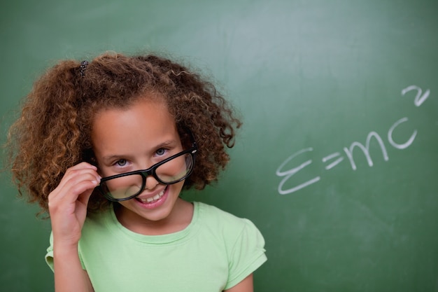 Colegiala inteligente mirando por encima de sus gafas