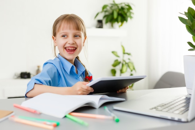 Colegiala inteligente con tableta digital en un aula. Niño en una escuela primaria. Educación y aprendizaje para niños.