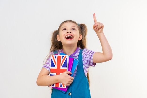 Una colegiala con un libro de texto en inglés señala con la mano el anuncio.