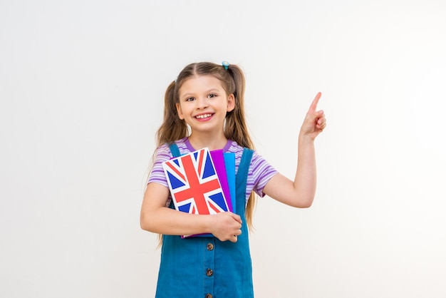 Una colegiala con un libro de texto en inglés señala con la mano el anuncio.