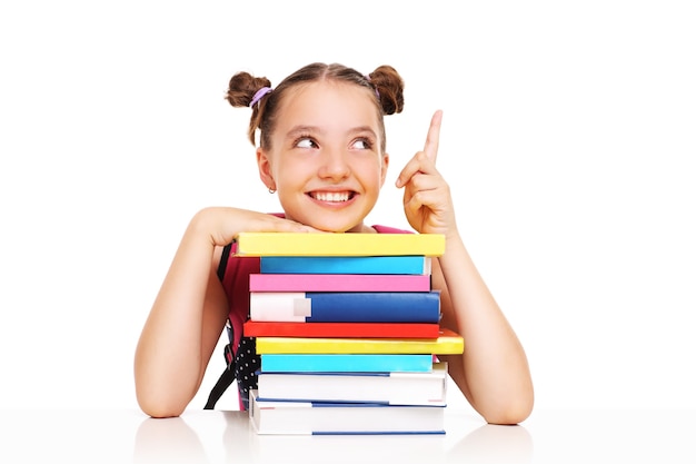 Foto una colegiala con libros apuntando a algo sobre fondo blanco.