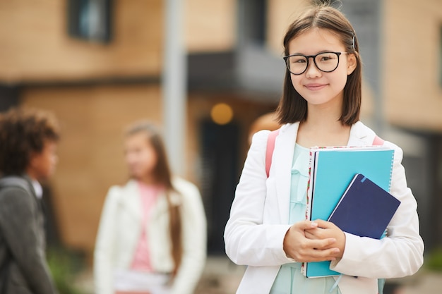 Colegiala con libros de pie al aire libre