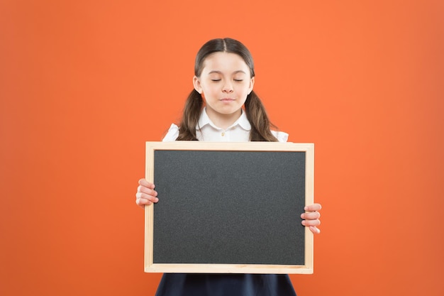 Colegiala linda pupila mantenga espacio de copia de pizarra Concepto de anuncio escolar Informar a los niños sobre los cambios en la vida escolar Buenas noticias para la comunidad de alumnos Programa educativo Información sobre el horario escolar