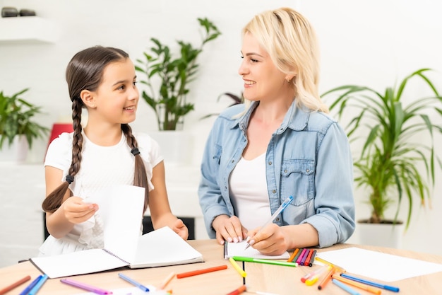 colegiala y madre juntas haciendo la tarea en casa.