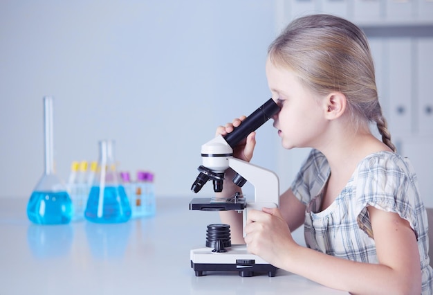 Colegiala mirando a través del microscopio en clase de ciencias