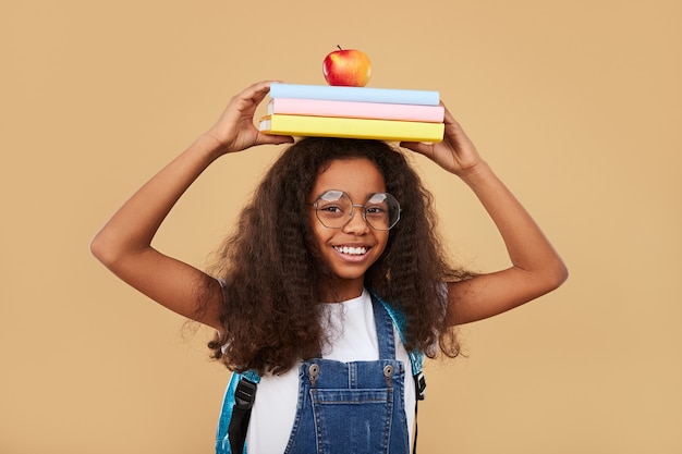 Colegiala negra inteligente con libros de texto y manzana