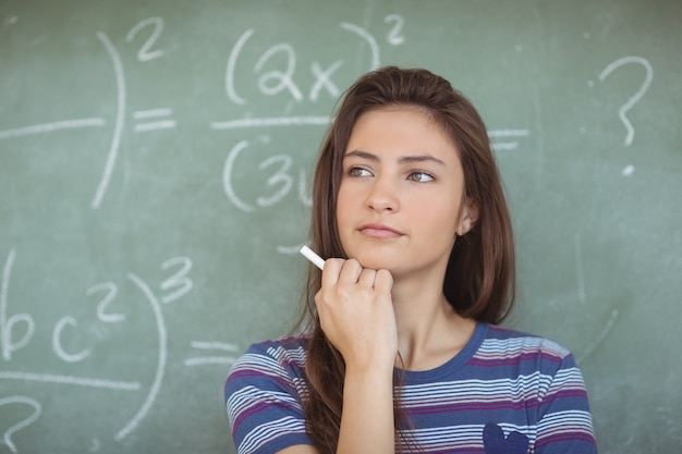 Colegiala pensativa que finge ser maestra en el aula