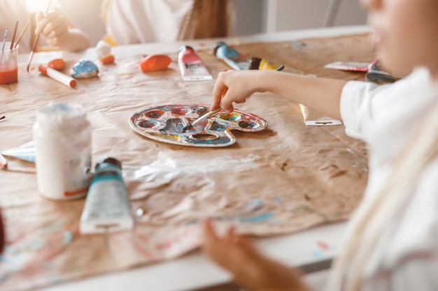Colegiala pintando sobre papel con pinturas de colores