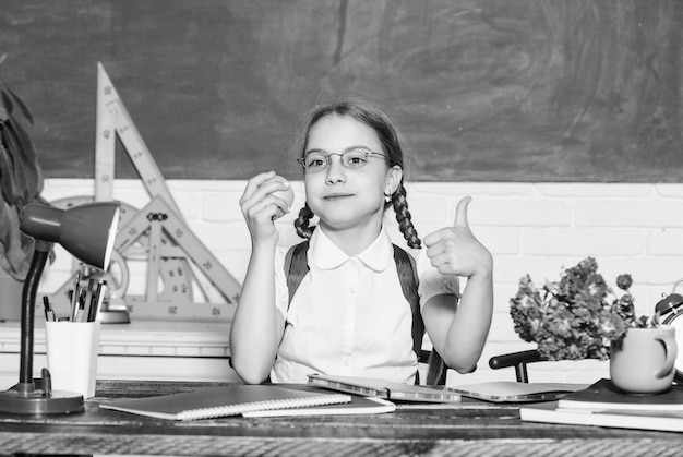 Colegiala sentarse escritorio pizarra fondo Niño estudiante en la escuela Niña niño pequeño comiendo bocadillo de manzana Vacaciones escolares Relajarse entre lecciones Concepto de vida escolar Estilo de vida saludable Infancia moderna