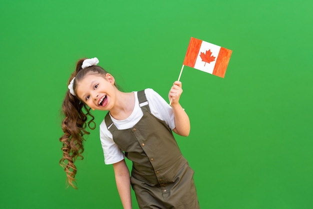 Una colegiala sostiene una bandera canadiense y se regocija. Kid está muy emocionado de estudiar en el extranjero.