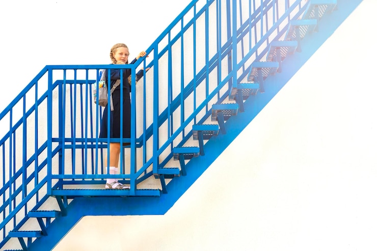 Colegiala sube las escaleras Concepto días escolares fecha de inicio siguiente etapa carrera escalera el comienzo del camino chica en uniforme con mochila Chica sube un escalón por las escaleras