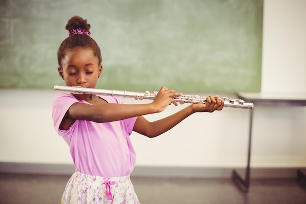 Colegiala tocando la flauta en el aula