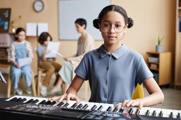 Colegiala tocando el piano en clase de música