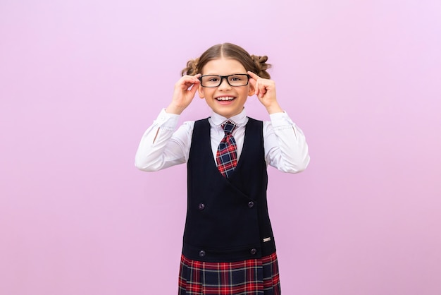 Una colegiala con uniforme escolar y gafas sobre un fondo aislado. Un estudiante sobre un fondo morado.